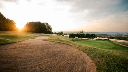 Golfplatz mit Sandbunker und Puttinggrün bei Sonnenuntergang