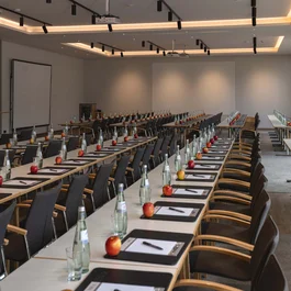Konferenzraum mit Tischen, Stühlen, Wasserflaschen, Äpfeln und Schreibmaterial
