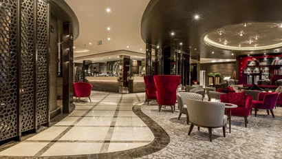 Luxuriöse Hotellobby mit roten und grauen Sesseln und moderner Beleuchtung