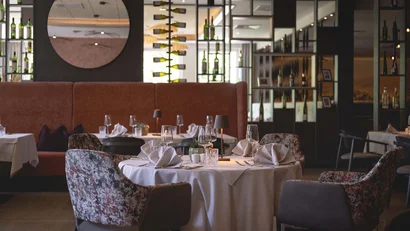 Elegantes Restaurant mit gedeckten Tischen und Weinflaschen an der Wand