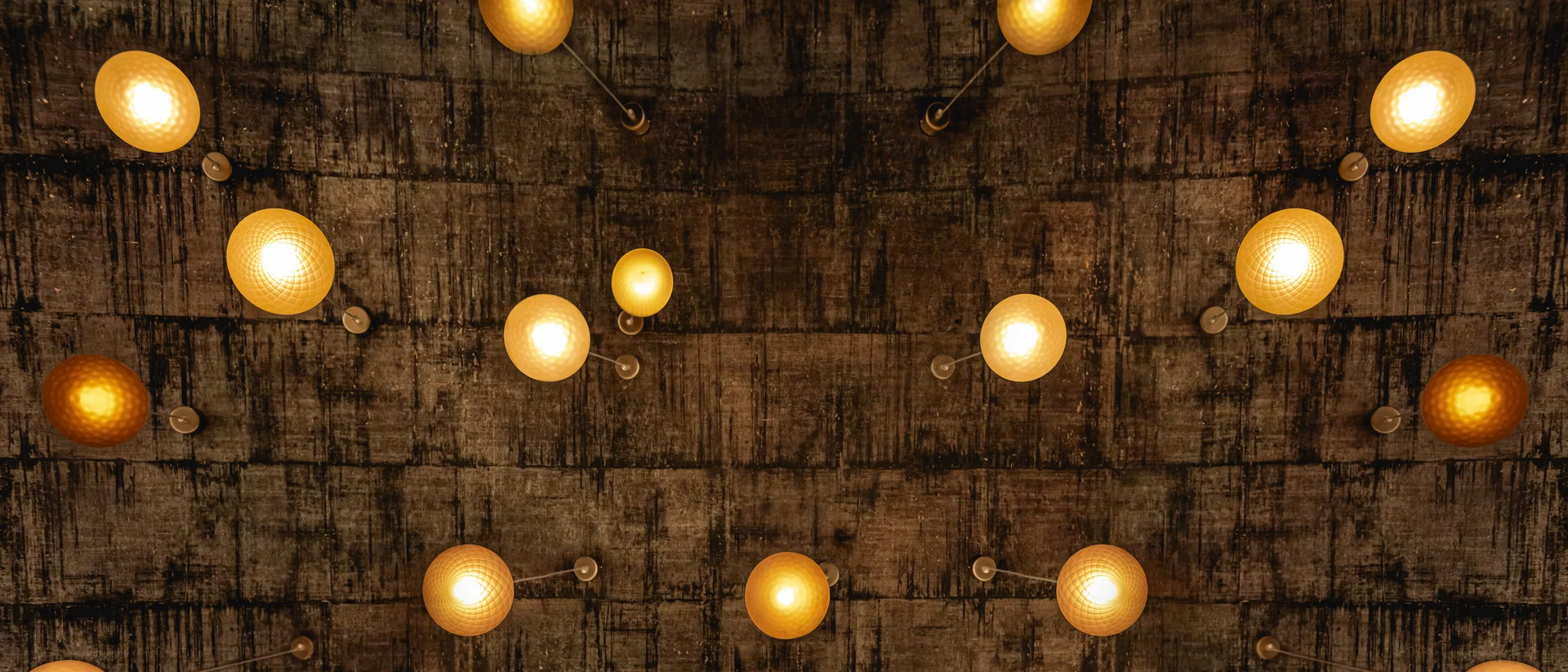 Land & Golf Hotel Stromberg Decke mit mehreren warmen kugelförmigen Hängelampen vor dunklem Hintergrund