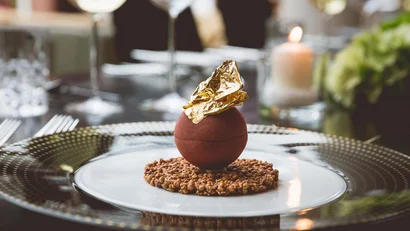 Schokoladendessert mit goldener Dekoration auf knusprigem Boden auf elegantem Teller