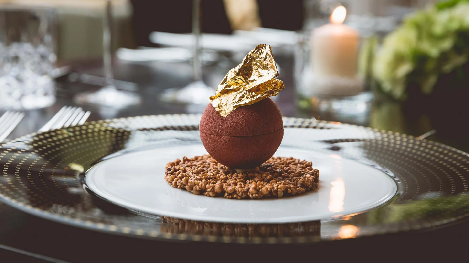Schokoladendessert mit goldener Dekoration auf knusprigem Boden auf elegantem Teller