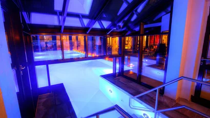 Innenpool mit blauem Licht, Glaswänden und Treppen mit Geländern