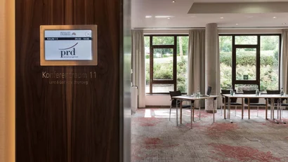 Konferenzraum 11 mit Tischen, Stühlen und großen Fenstern
