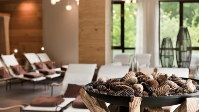 Gemütlicher Entspannungsraum mit weißen Liegestühlen und Dekoration aus Kiefernzapfen