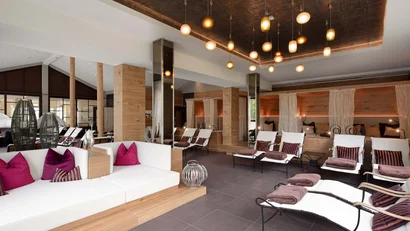 Moderne gemütliche Lounge mit weißen Sofas, Liegestühlen und warmen Pendelleuchten