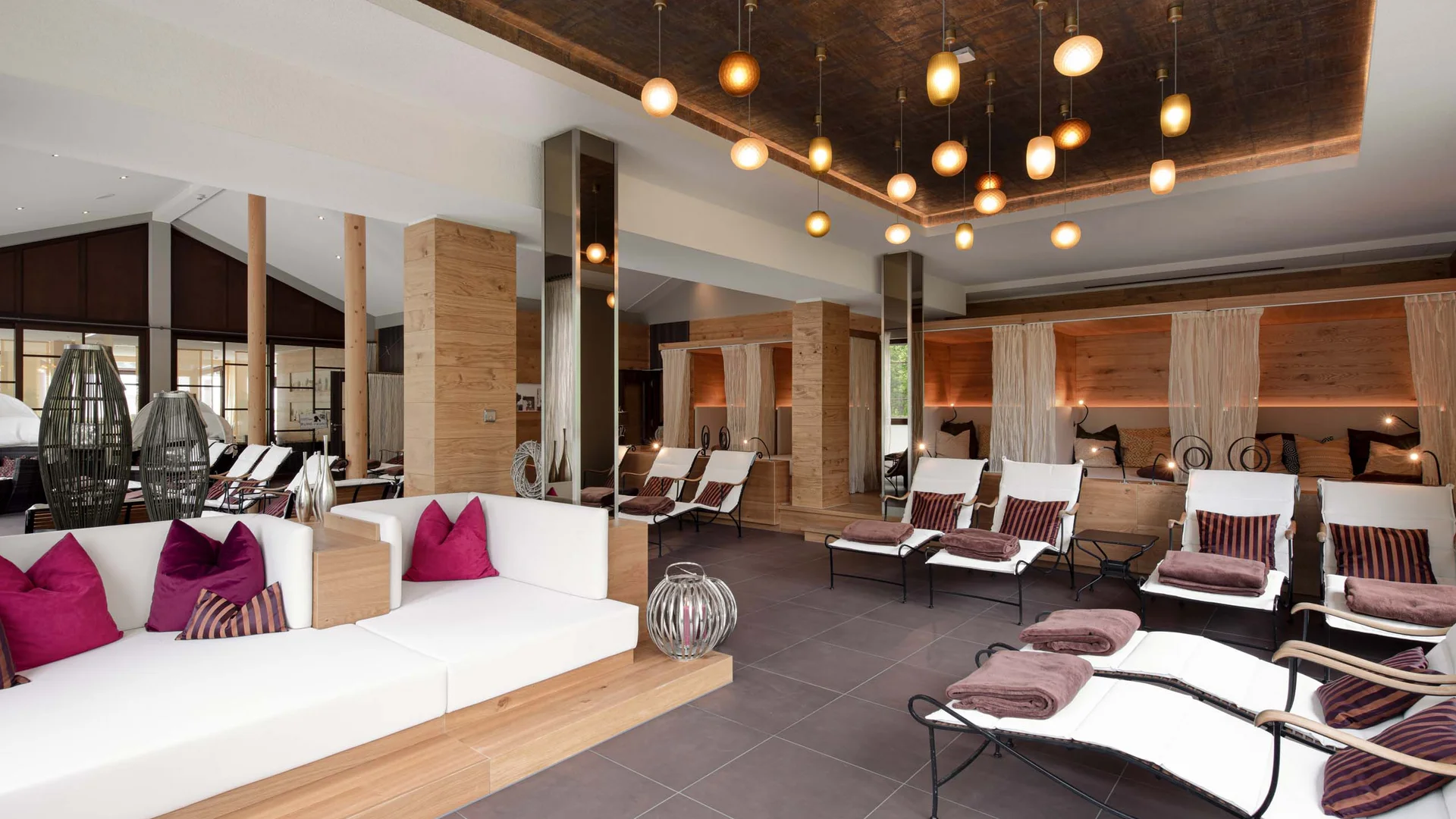 Moderne gemütliche Lounge mit weißen Sofas, Liegestühlen und warmen Pendelleuchten