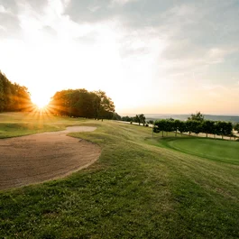 Golfplatz mit Sandbunker bei Sonnenuntergang und Blick über die Landschaft
