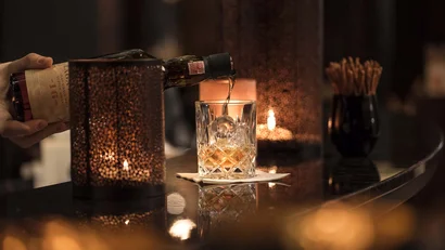 Whisky wird in ein Glas mit Eis in einer gemütlichen Bar eingeschenkt