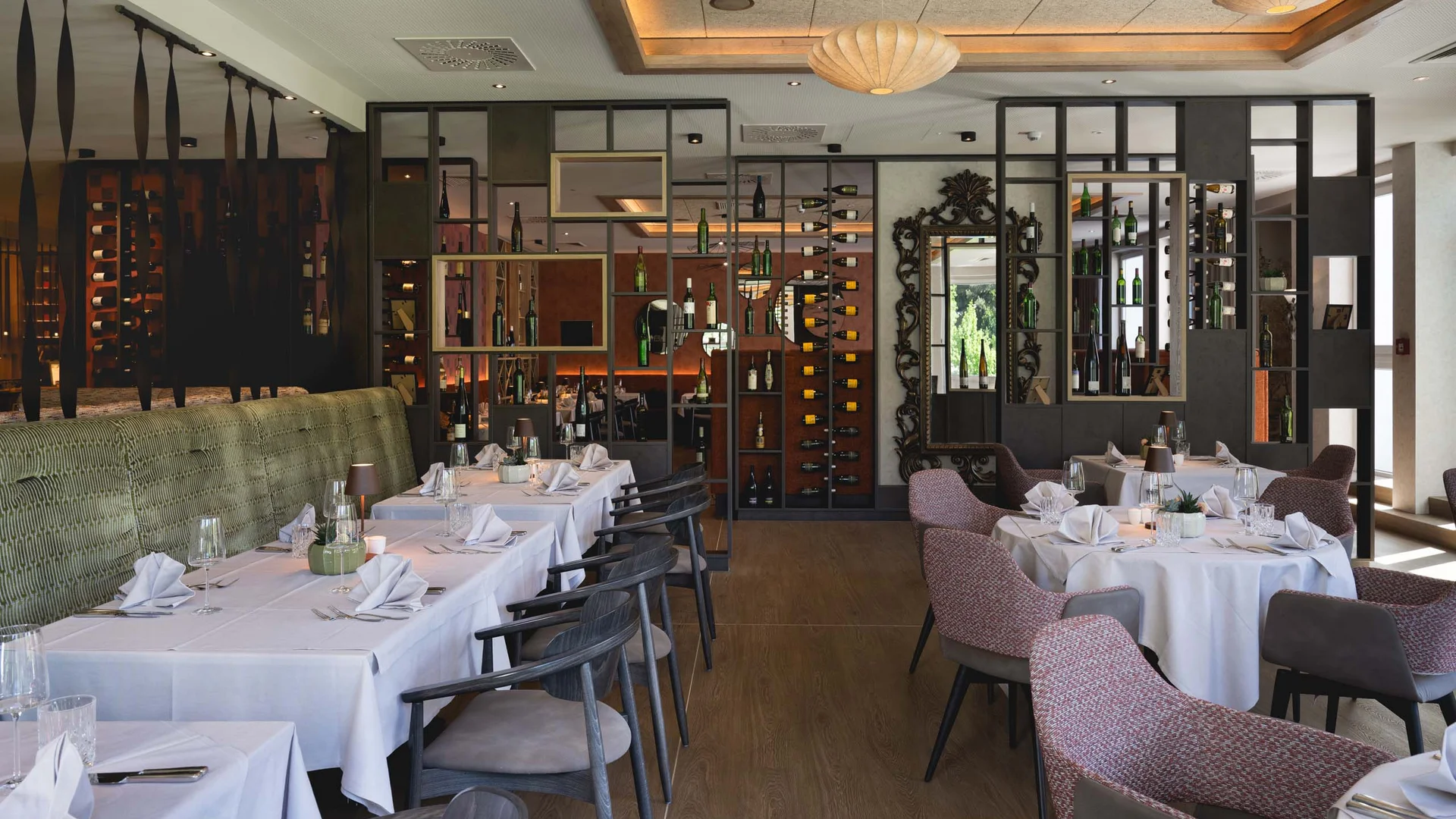 Elegantes Restaurant mit weißen Tischdecken und Weinregalen an der Wand