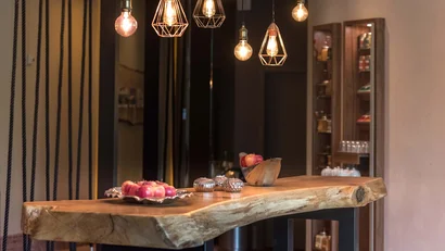 Hölzerner Tisch mit Äpfeln und stilvollen Lampen in modernem Raum