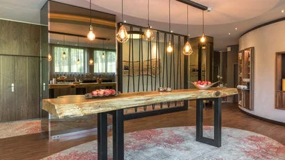 Moderner Raum mit rustikalem Holztisch und hängenden Edison-Glühbirnen