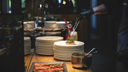Koch mit schwarzen Handschuhen dekoriert Gericht in Restaurantküche