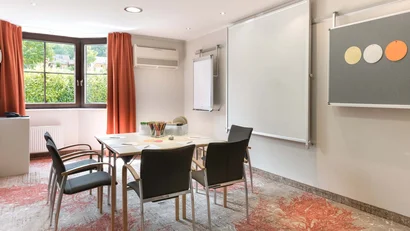 Kleiner Konferenzraum mit Tisch, Stühlen und Präsentationsflächen