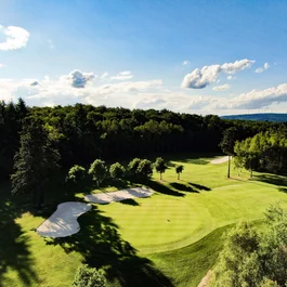 Grüner Golfplatz mit Sandbunkern und Bäumen an einem sonnigen Tag