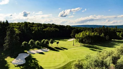 Grüner Golfplatz mit Sandbunkern und Bäumen an einem sonnigen Tag