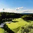 Grüner Golfplatz mit Sandbunkern und Bäumen an einem sonnigen Tag