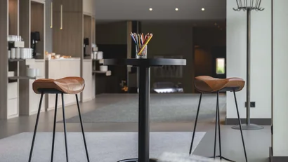 Moderner Sitzbereich mit hohem Tisch und zwei Lederhockern
