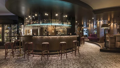 Moderne Hotelbar mit Lederhockern und dekorativer Beleuchtung