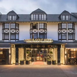 Eingang des beleuchteten Land & Golf Hotels Stromberg am Abend