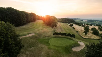Golfplatz mit Sandbunkern und Waldlandschaft bei Sonnenuntergang