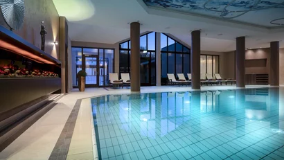 Hallenbad in einem Spa mit Liegestühlen und großen Fenstern