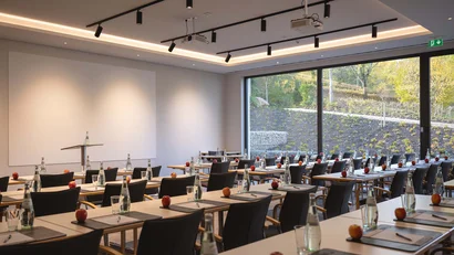 Moderner Konferenzraum mit Tischen, Stühlen, Wasserflaschen und Äpfeln