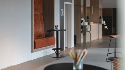 Moderne Hotellobby mit Sitzbank, Stehtischen und Kaffeestation