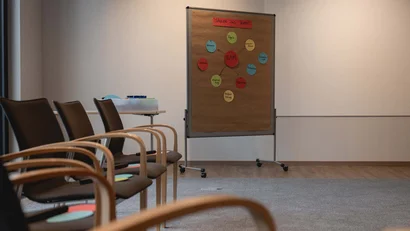 Leerer Seminarraum mit Stühlen und Flipchart mit Teamübersicht