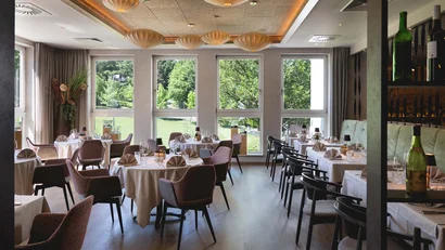 Elegantes Restaurant mit großen Fenstern und runden Tischen mit weißen Tischdecken