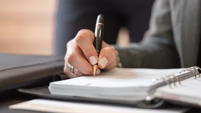 Hand hält Stift und schreibt in einen Planer