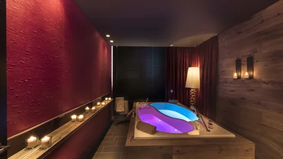 Modernes Badezimmer mit Holzdekor, Kerzenlicht und Badewanne mit bunter Beleuchtung