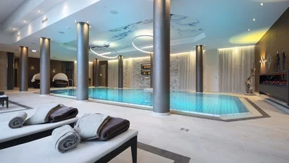 Moderner Innenpool im Spa mit Liegen und gerollten Handtüchern
