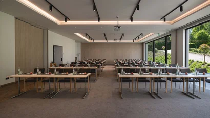 Moderner Konferenzraum mit Tischen, Stühlen und großer Fensterfront