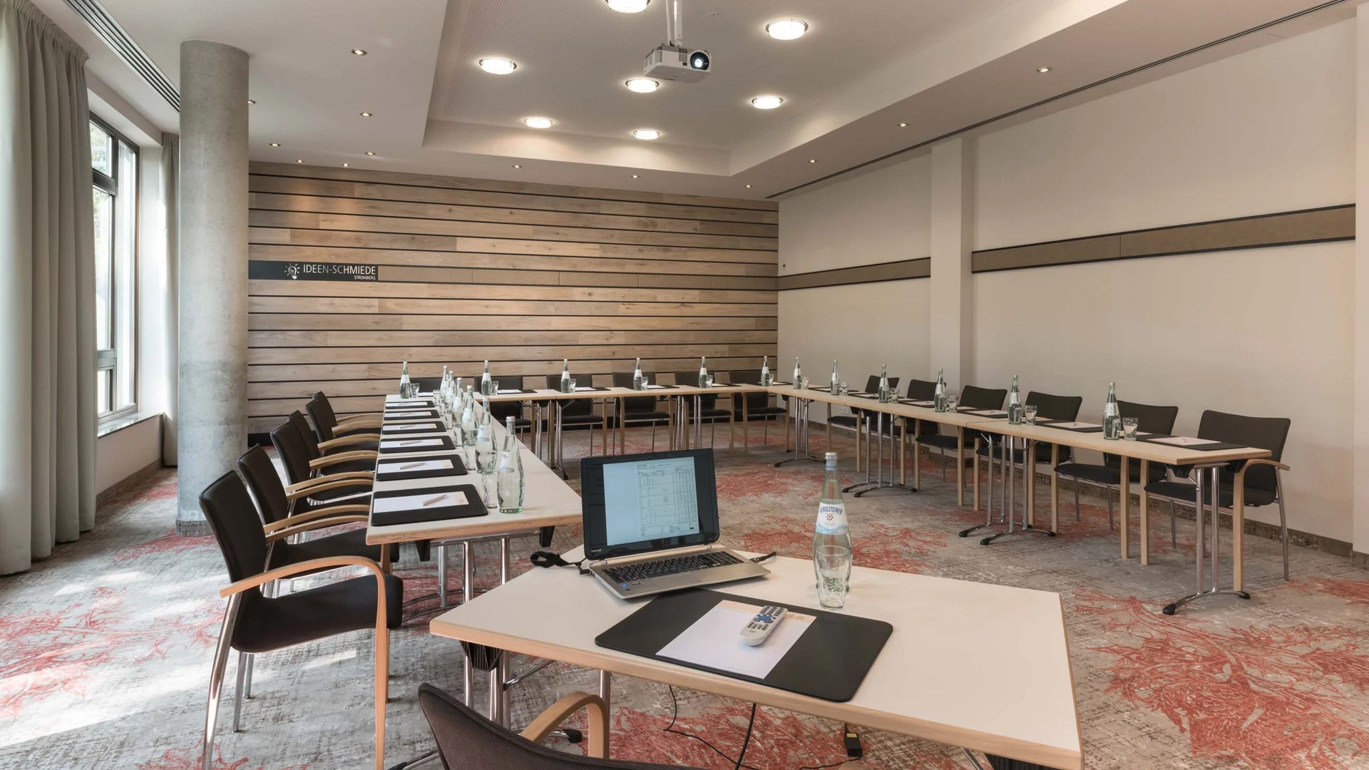 Moderner Konferenzraum mit U-förmigem Tisch und Laptop auf einem Tisch