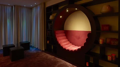 Gemütliche Sitzecke mit rundem, gepolstertem Sessel in einem dunklen Raum