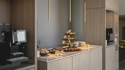 Buffet mit Gebäck, Desserts und Kaffeeautomat in modernem Raum
