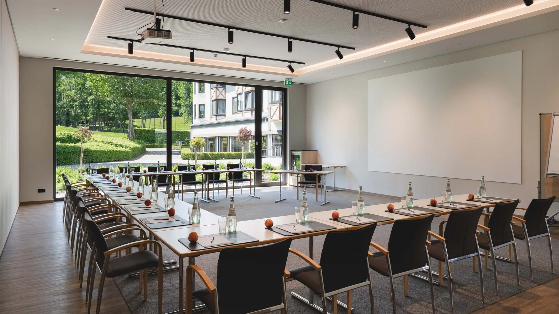 Konferenzraum mit U-förmigen Tischen und Blick auf Garten