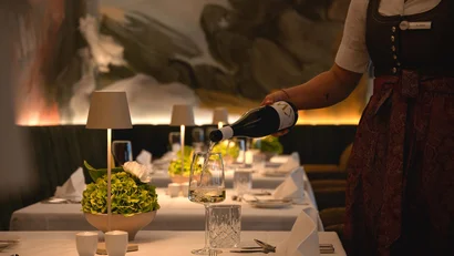 Kellnerin gießt Weißwein in einem elegant gedeckten Restauranttisch