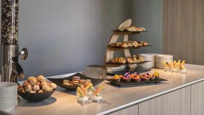 Buffet mit Gebäck, Macarons und Gemüsesticks in Gläsern