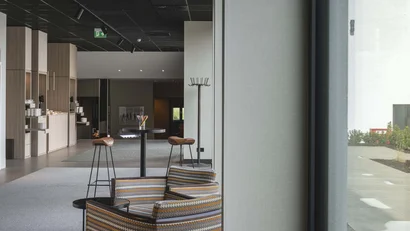 Moderne Lobby mit gemustertem Sessel, Stehtisch und Holzschränken