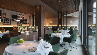 Elegantes Restaurantinterieur mit weißen Tischdecken und grünen Stühlen