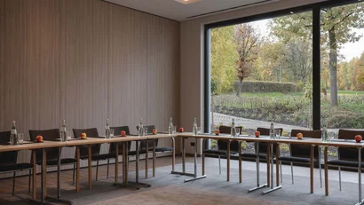 Besprechungsraum mit Tischen, Stühlen, Wasserflaschen und Äpfeln am Fenster mit Ausblick