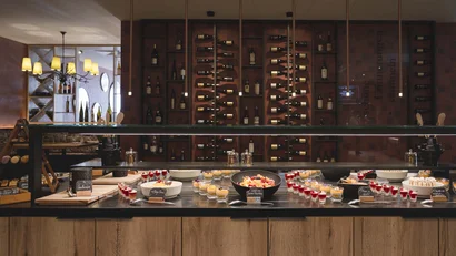 Buffet mit verschiedenen Desserts und Weinflaschen im Hintergrund