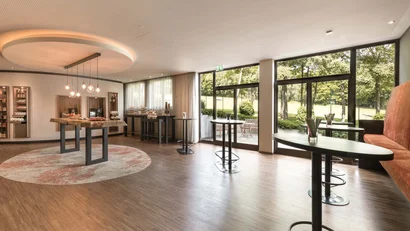 Heller Veranstaltungsraum mit Stehtischen und großem Fensterblick ins Grüne