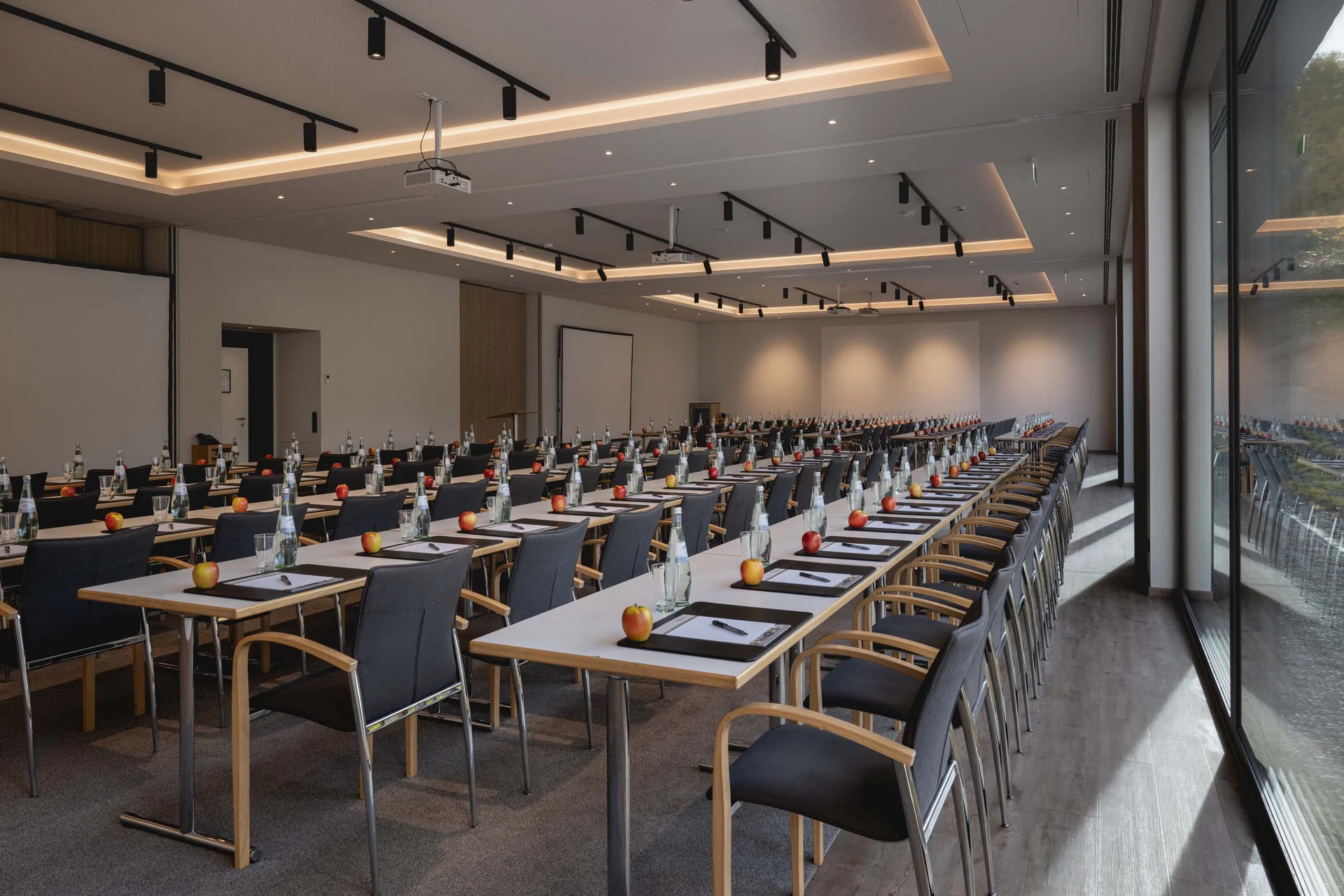 Konferenzraum mit Tischen, Stühlen, Äpfeln und Wasserflaschen vorbereitet