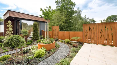 Moderner Garten mit Steingang, vielfältigen Pflanzen und Holzsichtschutzwänden