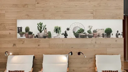 Drei weiße Sessel vor einer Holzwand mit Pflanzenregal