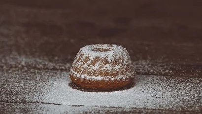 Kleine Gugelhupf mit Puderzucker auf dunklem Holztisch